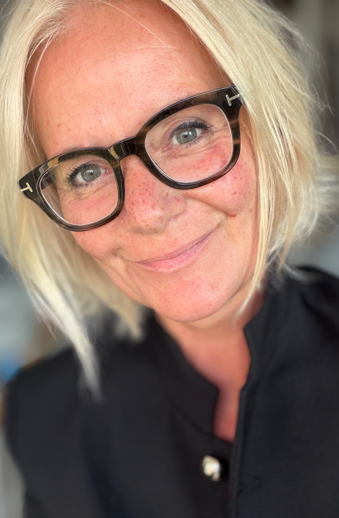 Andrea mit blondem Bob und dunkler Brille lächelt in die Kamera